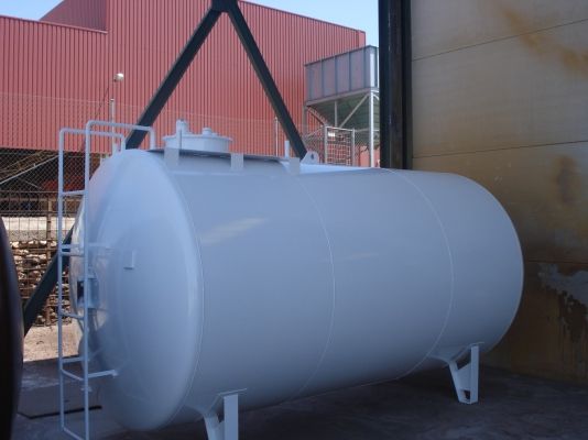 Depósito cilíndrico horizontal gris claro izado con eslingas junto a la nave