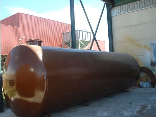 Depósito cilíndrico horizontal con imprimación marrón en el exterior del taller