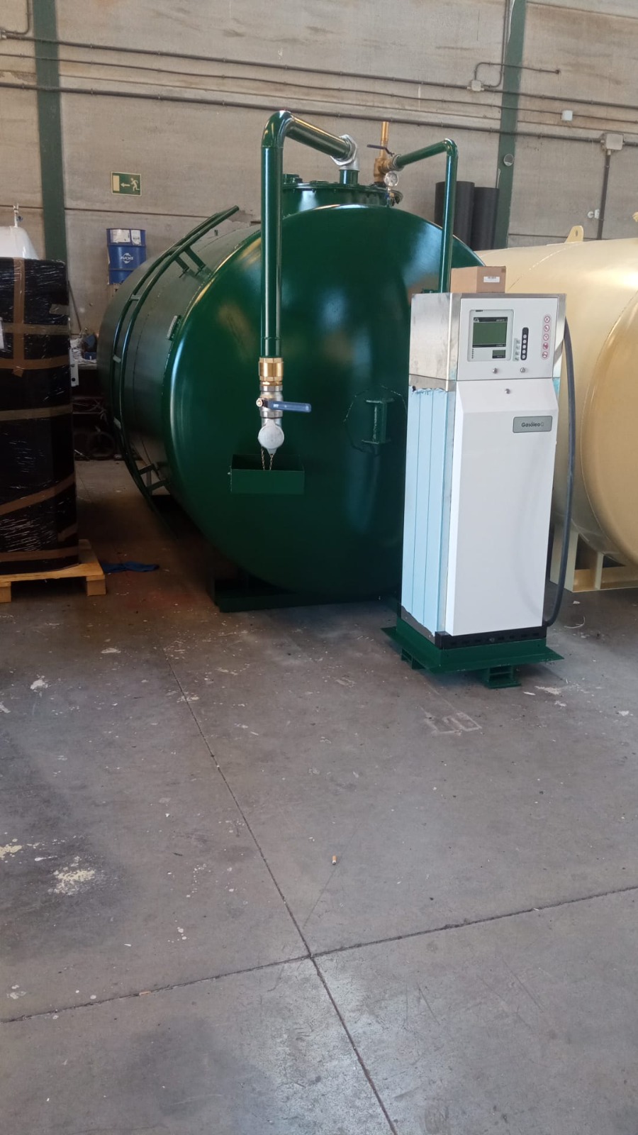 Depósito cilíndrico verde con valvulería, bandeja de recogida y surtidor con contador electrónico