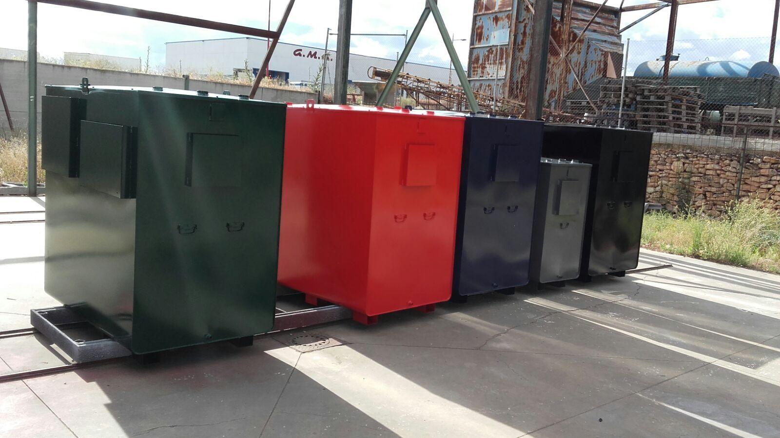 Cinco depósitos paralelepípedos de doble pared sobre bancada, pintados en verde, rojo, azul, gris y negro